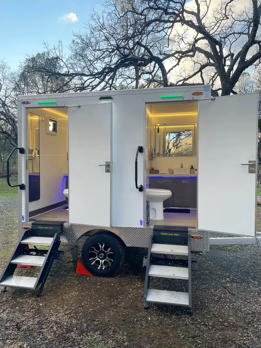 Two-stall restroom trailer with lit interiors and steps
