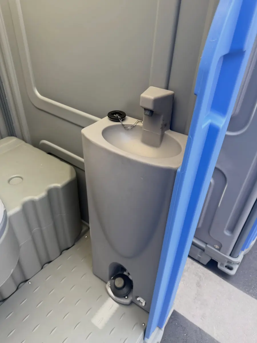 Inside a deluxe portable toilet with a foot-pump hand sink