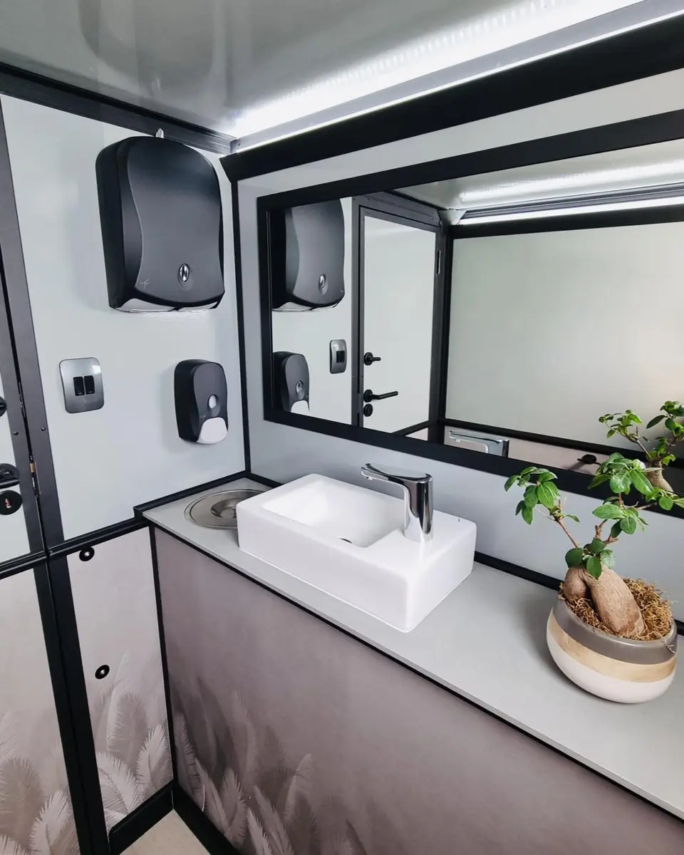 Restroom trailer vanity with white sink, mirror and soap dispenser