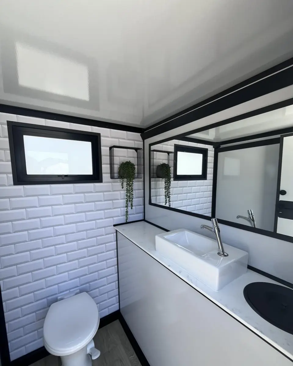 Restroom trailer stall with tile wall, sink and toilet