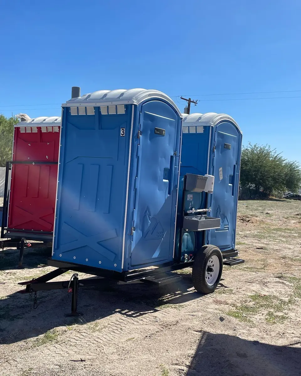 Porta potties on a towable trailer on dirt ground